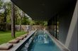 man walking beside a lap pool with wooden decking